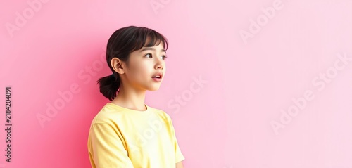 Teenage figure shushing, hand gesturing to the side against a pink backdrop, pink background, whisper