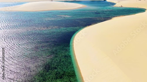 Aerial drone view of white sand dunes and a wide green lagoon under the afternoon sun, Lencois Maranhenses, Brazil