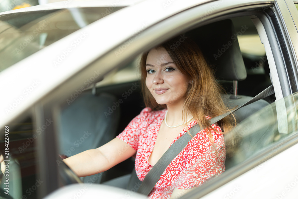 Obraz premium Positive young adult woman driving car during solo trip, side view