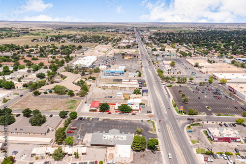 Aerial view of a commercial strip mall and surrounding suburban town infrastructure with urban development city infrastructure parking lot retail building road network town landscape small town