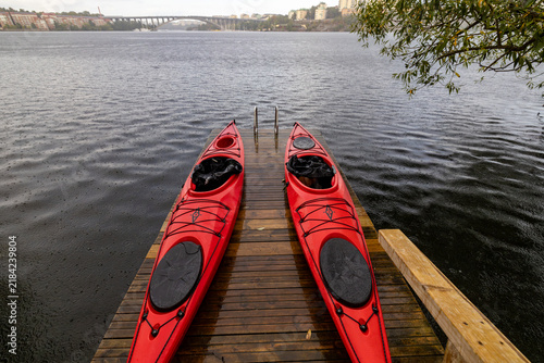 Stockholm, Sweden Two red kayaks sit on a pier in the rain on the Stora Essingen island.