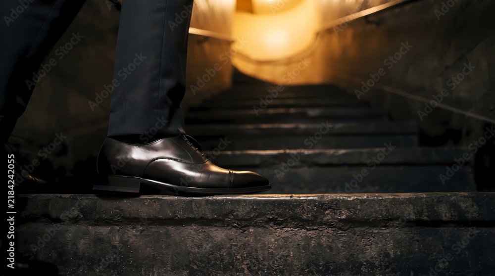 Obraz premium Elegant Businessman In Formal Shoes Walking Up Dark Stone Stairs Into Warm Golden Light Represents Success And Career Advancement