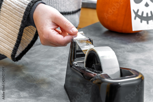Canvastavla Young woman pulling clear adhesive tape from desk dispenser