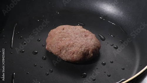 Grilled hamburger steak patty with seared crust cooking on a black griddle, camera zooms in and pans across the surface