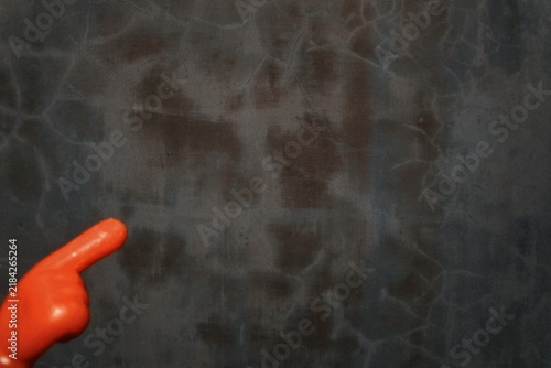 Small orange plastic novelty toy with a unique rounded shape placed on a dark textured surface, creating a simple abstract still life with vivid color contrast.