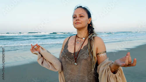 Фотография Woman standing in a meditative pose on a sandy beach