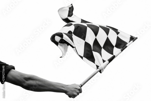 Person waving black and white checkered flag in dynamic motion, high contrast black and white photography, energetic sports event or race finish line celebration, triumphant victory moment