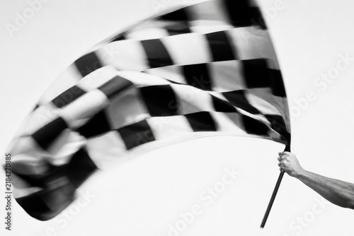 Dynamic black and white checkered flag waving in motion, high-speed racing event, victory, competition, abstract motion blur, sports photography, intense focus, dramatic lighting