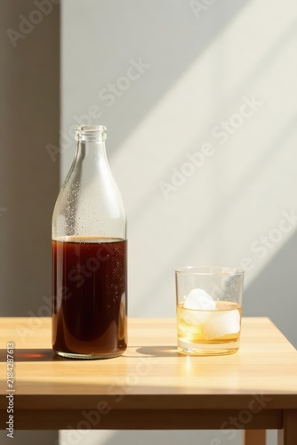 Sunlit Still Life A Bottle of Dark Beverage and a Glass with Ice