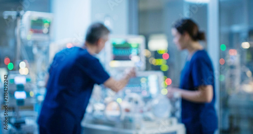 Medical professionals in scrubs are attending to a patient in a hospital setting, surrounded by advanced medical equipment and monitors.