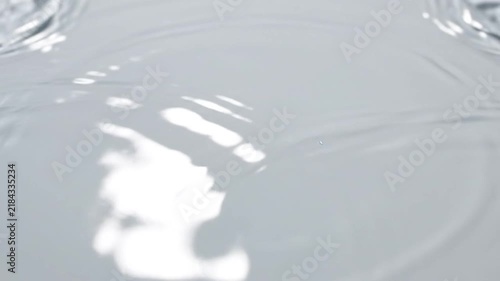 A single clear water droplet creates a ripple on the surface