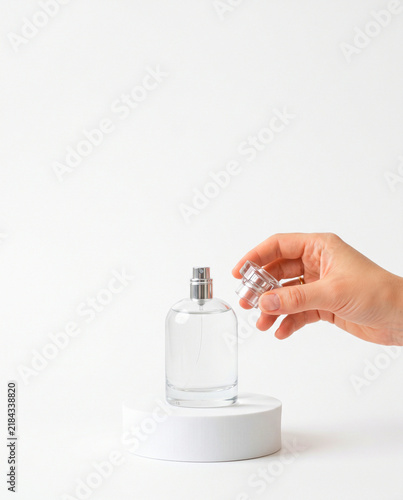 Hand Opening Clear Glass Perfume Spray Bottle on White Podium
