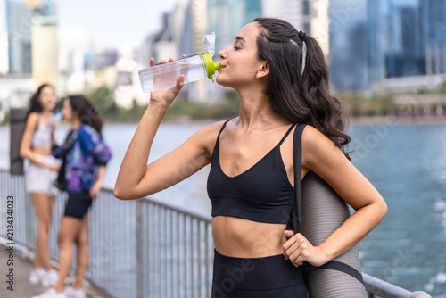 Принти на полотні A group of three Hispanic women in sportswear, in a triumphant, celebratory mood, toast with their water bottles after a workout with yoga mats over their shoulders and bottles in hand