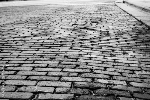 Foto Low-angle, monochrome view of a weathered brick street receding into the distance