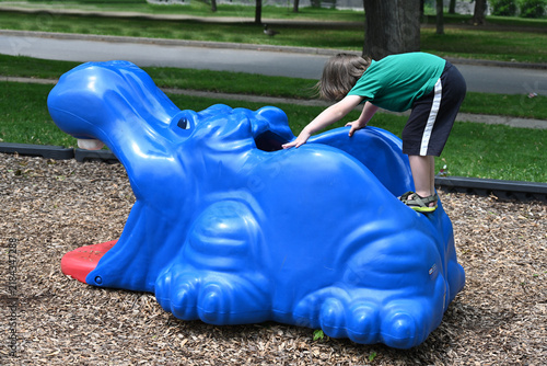 Child playing inside a blue hippo on a playground