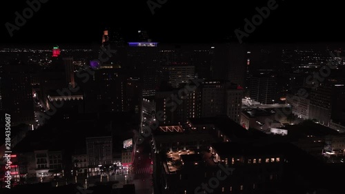 Downtown New Orleans, Louisiana buildings and skyscrapers are shown at night in an aerial approaching view.