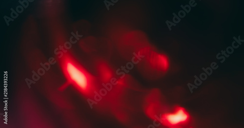 Bokeh red light. Lens glare. Defocused neon color optical vibrant gleam illuminated flash on abstract visual dark black art background.