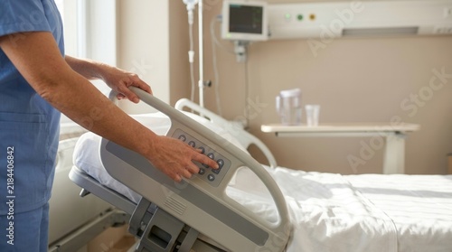 Nurse adjusting hospital bed controls, modern healthcare setting, patient care, comfort, technology in medicine
