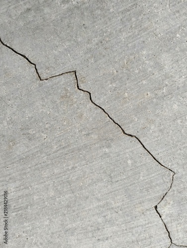 Grey concrete surface texture with deep crack lines running horizontally.