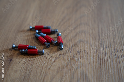 Red furniture connector screws on wooden surface