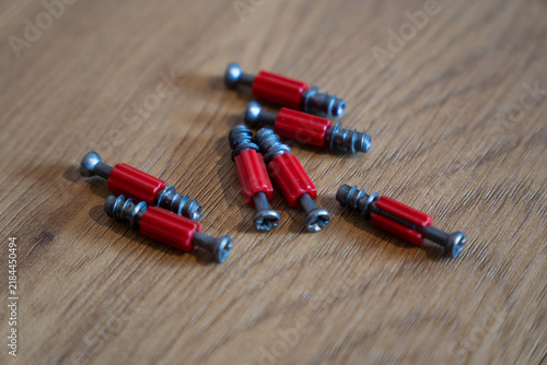 Red furniture connector screws on wooden surface
