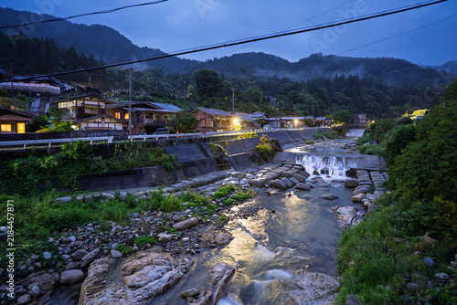 Mountain village lights reflect on water in river at dusk - Tsumago-Juku, Nagano, Japan