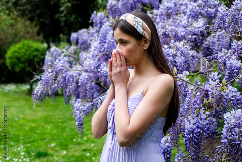 Quadro su tela Young woman sneezes into tissue