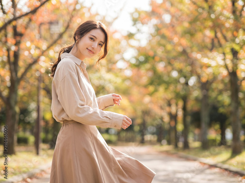 Naklejka 秋の並木道を散策しながら振り返る笑顔の女性