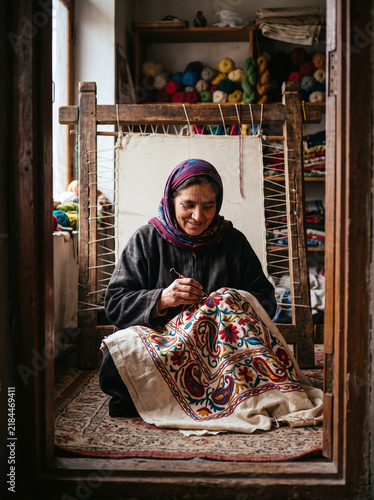 Kashmiri artisan woman embroidering traditional crewel tapestry in workshop