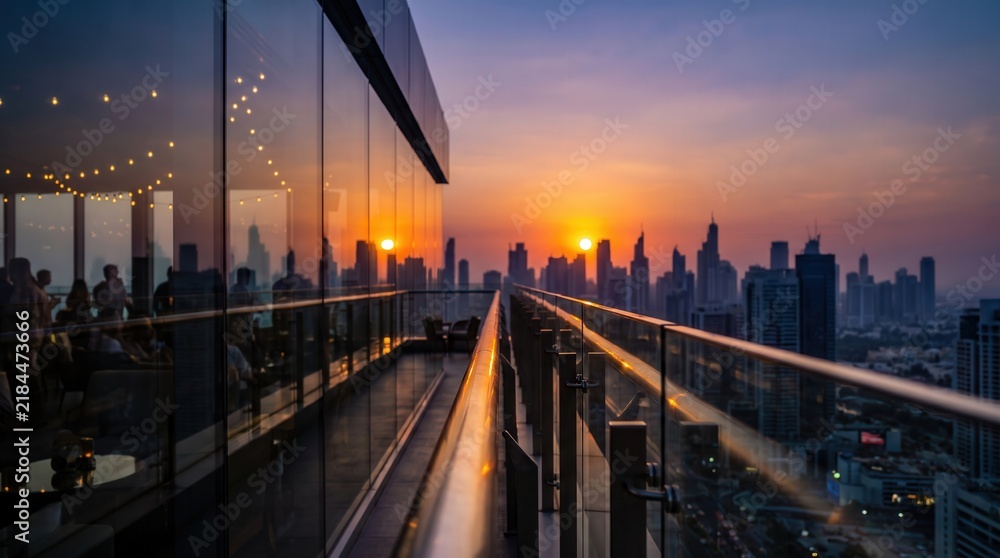 Obraz premium Modern rooftop terrace with glass railing overlooking city skyline at sunset, capturing urban luxury lifestyle and golden hour ambiance for travel promotion and real estate marketing.