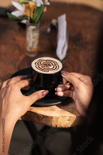 Картината върху платно Hands holding a coffee cup with cinnamon at a cozy café