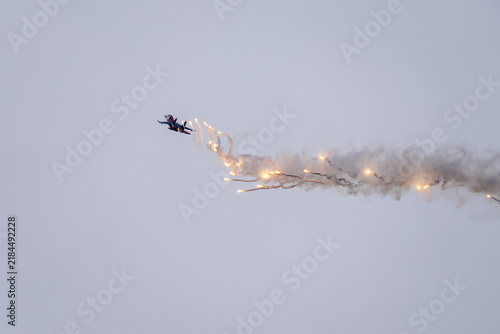 an aviation show in the sky. Modern jet fighter shooting fire flares rockets with sparks. Airplane deploying . fire protection IRCM. traps for air defense missiles
