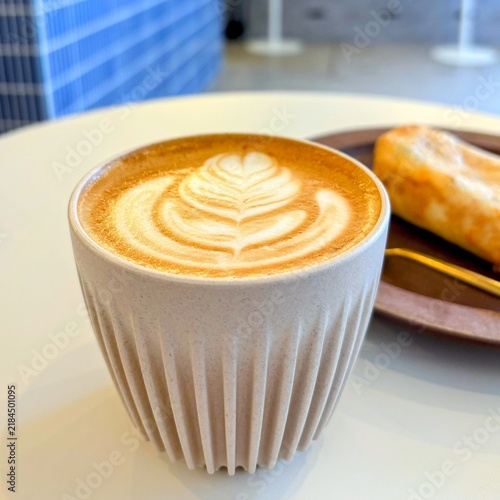 Foto Hot cafe latte with latte art served in a sustainable ribbed cup on a white table at a specialty coffee shop with a pastry in Japan