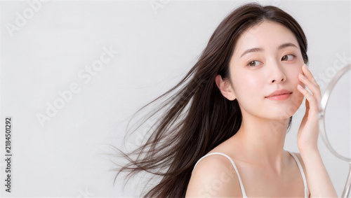 卓上鏡を見ながら頬に手を添える女性