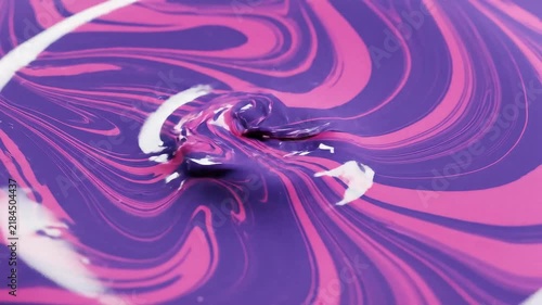 Close-up of purple and pink marbled paint swirling with white liquid drops, creating a vivid abstract fluid art background.