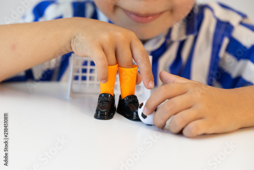 A boy plays finger football. The child plays with a toy with small shoes and a ball. A model of a football for children's play.