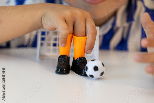 A boy plays finger football. The child plays with a toy with small shoes and a ball. A model of a football for children's play.