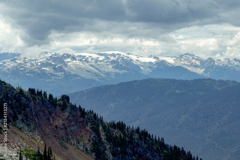 Fototapeta premium Majestic mountain range with snow-capped peaks under a cloudy sky, Blackcomb Gondola. Whistler, BC, Canada