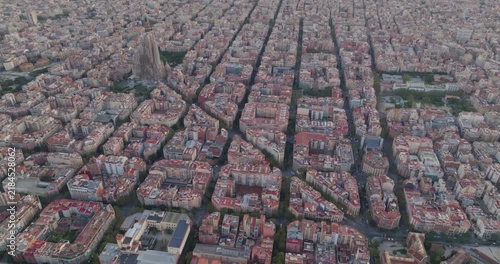 Cinematic aerial of Barcelona city skyline. Drone fly over Eixample residential famous urban grid and Sagrada Familia cathedral with morning sunrise cityscape. Catalonia, Spain. Travel Destination.
