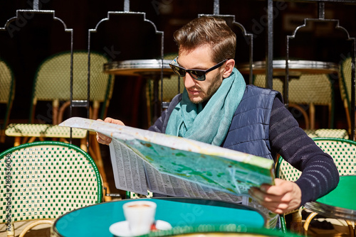 Фотография Man, travel and map at outdoor cafe for destination, sightseeing or directions to location