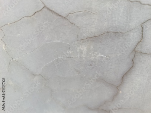 Foto sA close-up shot of a grey concrete surface with a network of fine cracks and weathered textures, showing a rustic and aged aesthetic