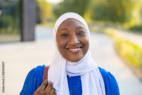 Konstfotografi A happy African American Muslim woman wearing a white hijab and blue dress smile