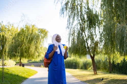 Принти на полотні A smiling African American Muslim woman wearing a blue dress and white hijab wal