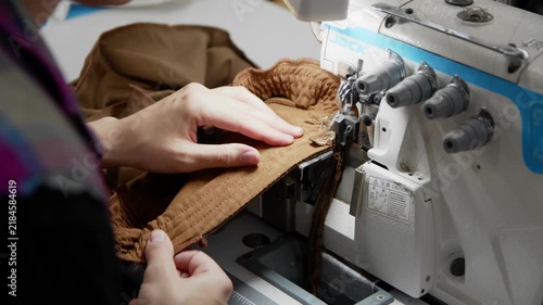 Women's hands sew on a sewing machine at a factory.