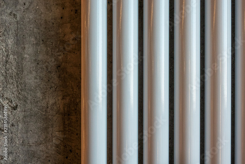 фотографія Modern tubular radiator sections on raw concrete wall