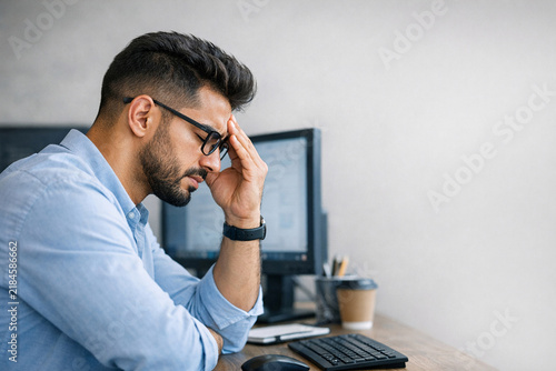 Man in suit with hands on head, struggling with workload