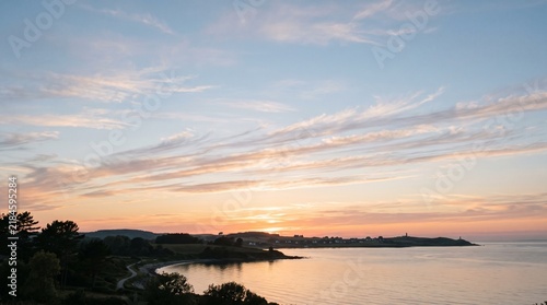 Coastal bay at sunset with orange sky and calm water reflection
