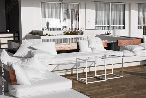 Soft white sofa with pillows on the  background of windows with reflection of sea.