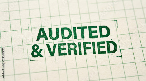 Audited and verified stamp on grid paper representing compliance with esg reporting standards for trustworthy documentation and transparency