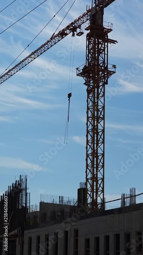 Tower crane operating above a modern construction site with unfinished concrete structure, representing urban development, building progress, engineering and growth of modern cities